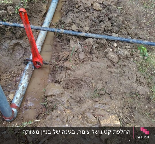 צינורות מים באדמה עם מפתח צינורות אדום